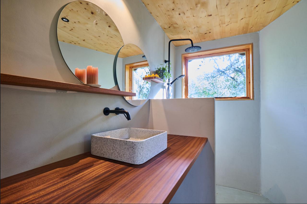 Wide view of the bathroom with black fittings and a window onto the trees
