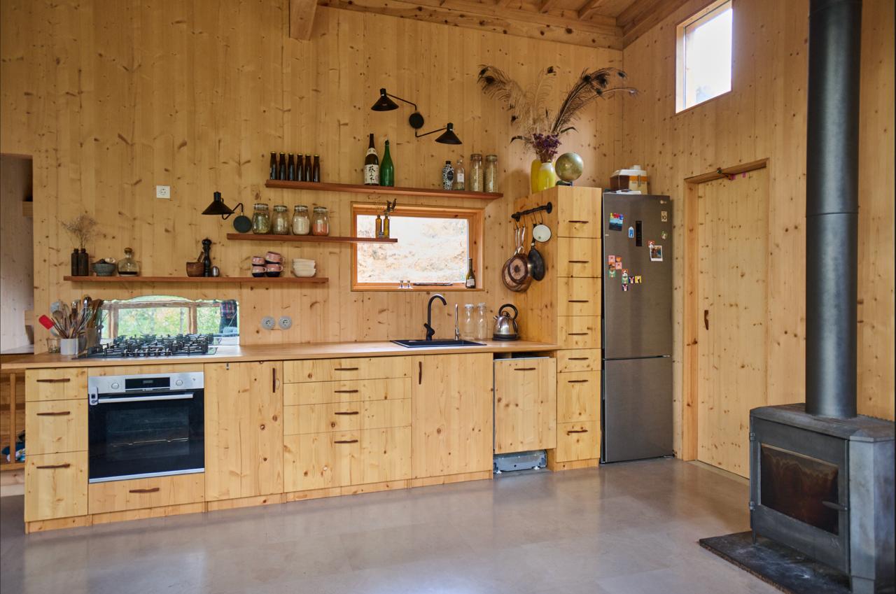 Pine kitchen with open shelves, a wood stove and a small high window